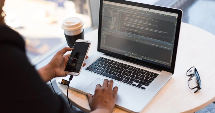 An image of a person using a laptop and cellphone