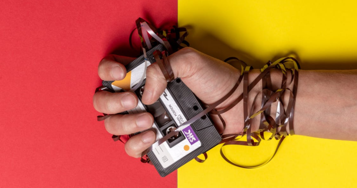 A person holding a damaged cassette tape