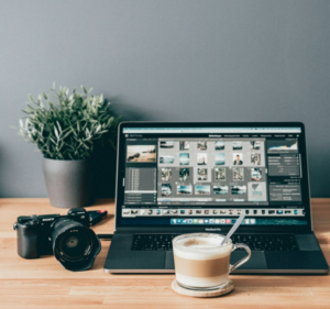 An image of a laptop, a camera, and a cup of coffee 