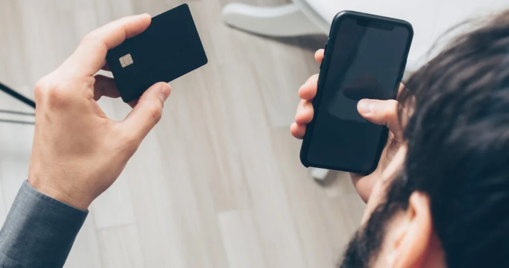 An image of a man holding a phone and card