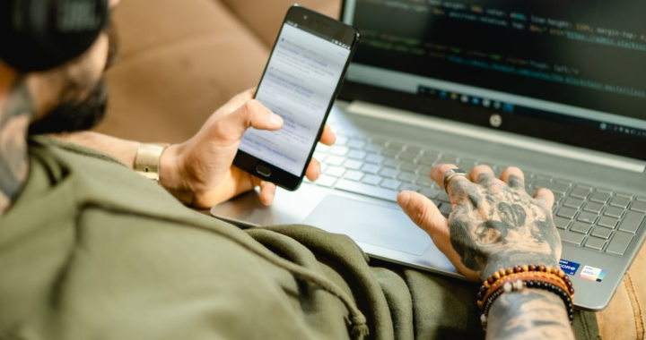 An image of a man using a laptop and mobile