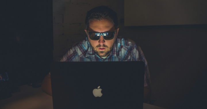 person wearing glasses looking at a laptop