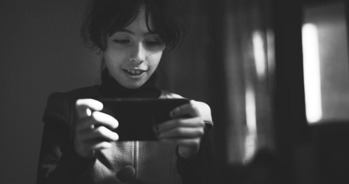 A black-and-white shot of a child using a mobile phone