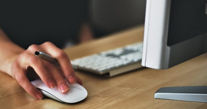 A cropped image of a person holding an Apple magic mouse