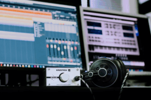 focus on headphones placed in front of two screens with audio graphs and keys