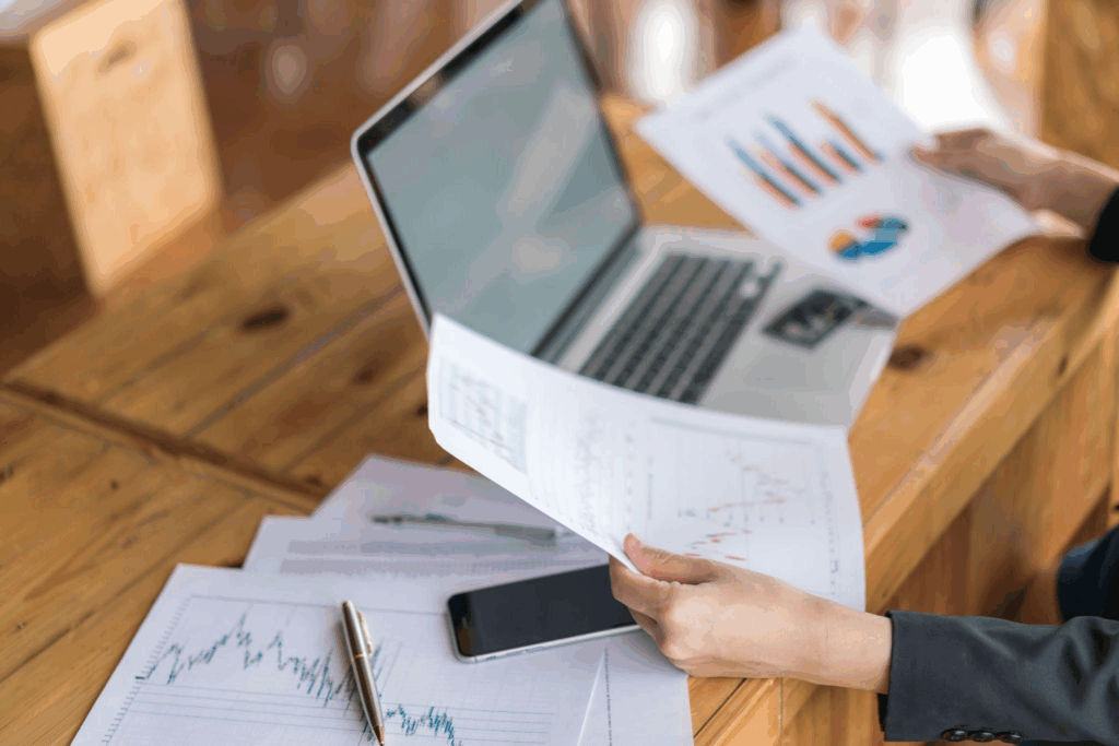 close-up of a woman going through documents placed next to her laptop